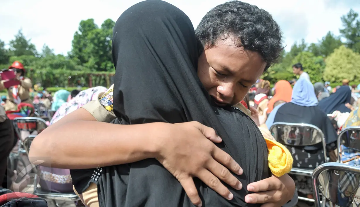 Anggota Kwarnas Gerakan Pramuka menangis sambil memeluk ibunya dalam kegiatan "Membasuh Kaki Ibu" secara massal di Taman Wiladatika Cibubur, Jakarta, Rabu (21/12). Aksi massal membasuh kaki ibu itu memperingati Hari Ibu 2016. (Liputan6.com/Yoppy Renato)