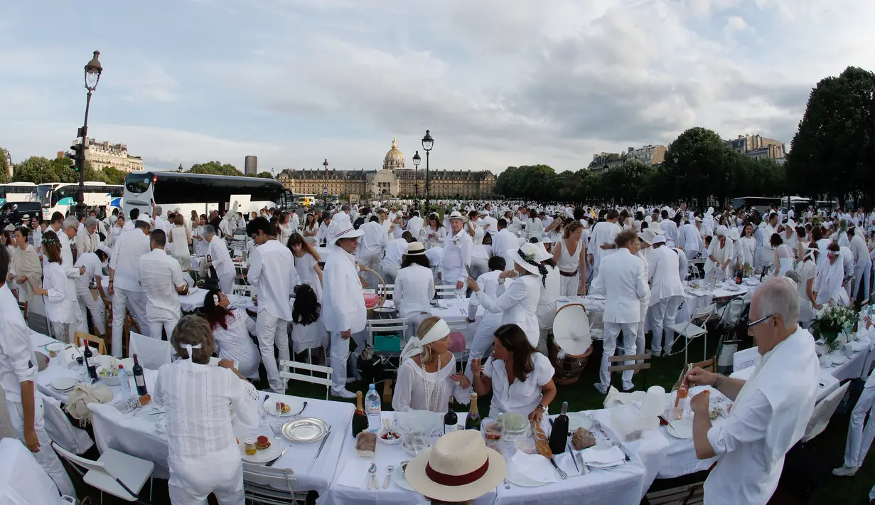 Orang-orang berpakaian putih berkumpul bersiap untuk makan malam bersama atau "Diner en Blanc" yang ke-30 di Paris, Prancis (3/6). Tempat dilaksanakannya acara ini akan dirahasiakan oleh penyelenggara hingga 2-1 jam sebelum dimulai. (AFP/Francois Guillot)