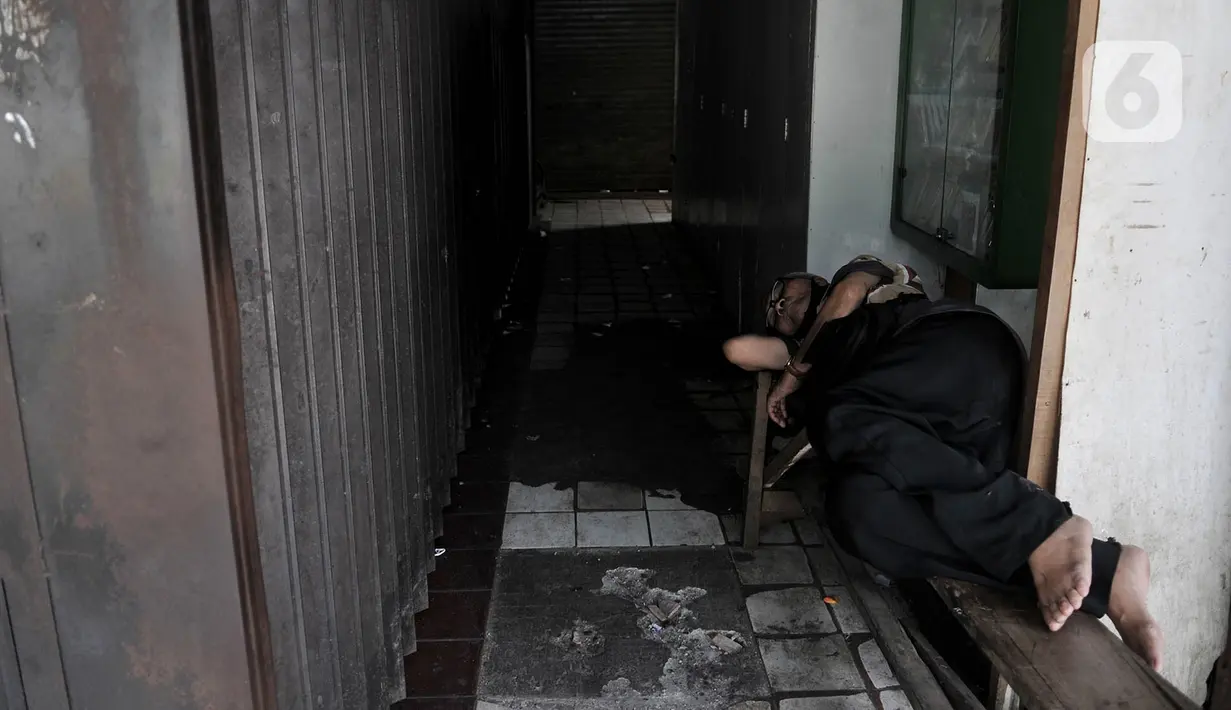 Pedagang tertidur di depan toko yang ditutup sementara di Pasar Perumnas Klender, Jakarta, Rabu (10/6/2020). Pasar Perumnas Klender terpaksa ditutup sementara setelah ditemukannya sebanyak 20 pedagang postif Covid-19. (merdeka.com/Iqbal S. Nugroho)