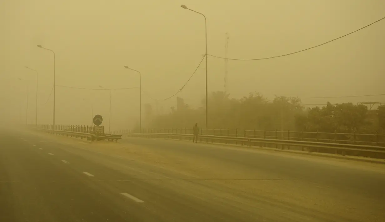<p>Seorang pria berjalan di jalan yang sepi selama badai pasir Musim Semi di ibukota Irak, Baghdad (5/5/2022). Irak kembali diselimuti lapisan jingga tebal karena mengalami serangkaian badai debu terbaru yang semakin sering terjadi. (AFP/Sabah Arar)</p>