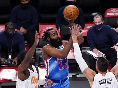 Pebasket Brooklyn Nets, James Harden, berusaha melewati pebasket Orlando Magic, Nikola Vucevic dan Dwayne Bacon pada laga NBA, Sabtu (16/1/2021). Nets menang dengan skor 122-115. (AP Photo/Mary Altaffer)