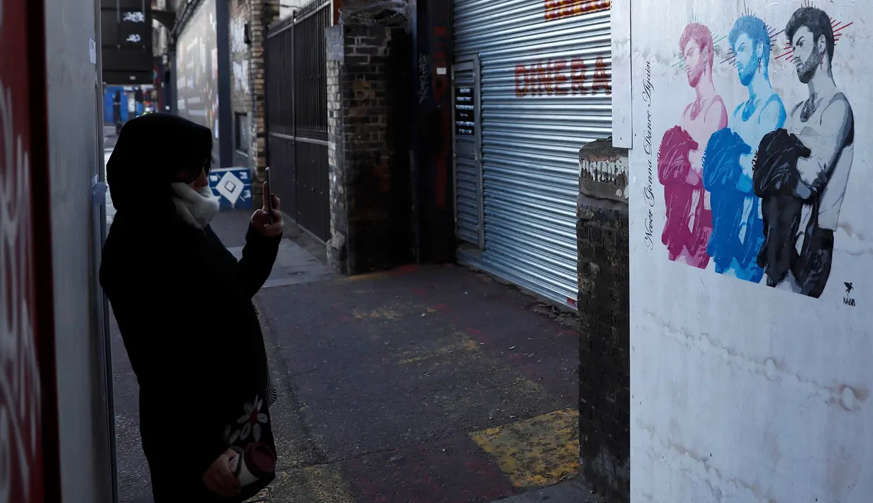 Seorang wanita mengambil gambar mural musisi asal Inggris, George Michael, di Shoreditch, London timur, 29 Desember 2016. Mural itu diciptakan seorang seniman jalanan Pegasus sebagai penghormatan terhadap mendiang George Michael. (REUTERS/Stefan Wermuth)