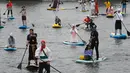 Orang-orang mengenakan kostum saat mendayung "paddle board" di Sungai Fontanka pada festival SUP (Stand Up Paddle)-Surfing di St.Petersburg, Rusia, Minggu (12/8). Dalam paddling, papan digerakkan dengan cara mendayung sambil berdiri. (AP/Dmitri Lovetsky)
