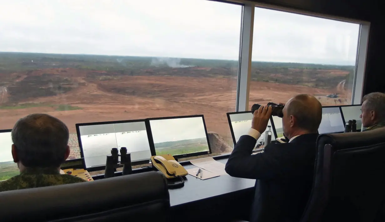 Presiden Rusia Vladimir Putin (tengah) saat menyaksikan latihan militer Rusia Zapad-2017 dengan Belarus di Luzhsky di wilayah Leningrad (18/9). Sekitar 70 pesawat dan helikopter juga ikut melakukan simulasi perang. (AFP Photo/Sputnik/Mikhail Klimentyev)