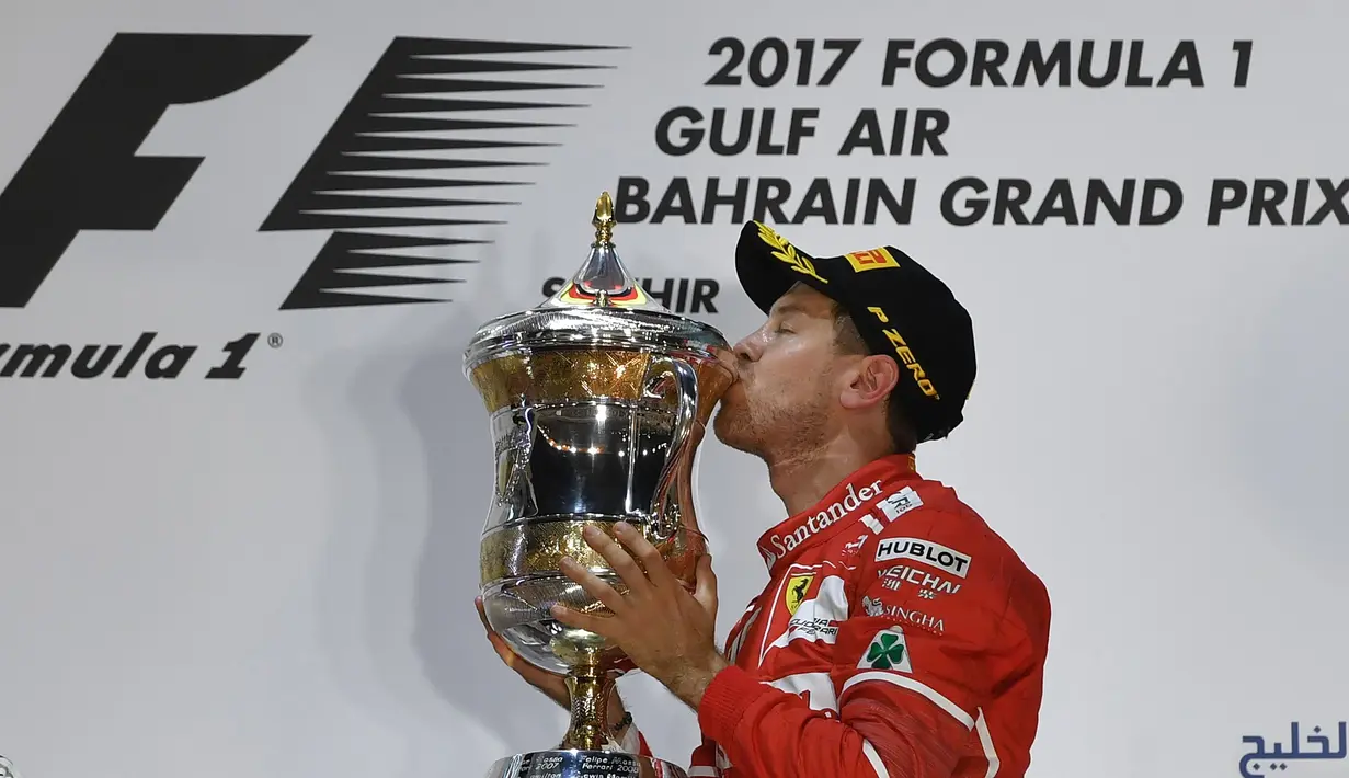 Sebastian Vettel mencium trofi juara yang diraihnya pada balapan F1 GP Bahrain di Sirkuit Sakhir, Manama, Minggu (16/4/2017).  (AFP/Andrej Isakovic)