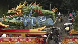 Orang-orang berjalan melewati patung naga di Kuil Hongludi Nanshan Fude untuk menandai hari ketiga Tahun Baru Imlek di New Taipei City, Taiwan, Selasa (24/1/2023). (Sam Yeh/AFP)