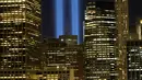 Sorotan cahaya kembar berwarna biru untuk peringati peristiwa serangan 9/11 di Kota New York, Minggu (10/9). Dua cahaya biru tegak lurus itu melambangkan menara kembar WTC yang menjadi sasaran serangan bunuh diri tersebut. (AP Photo/Mark Lennihan)