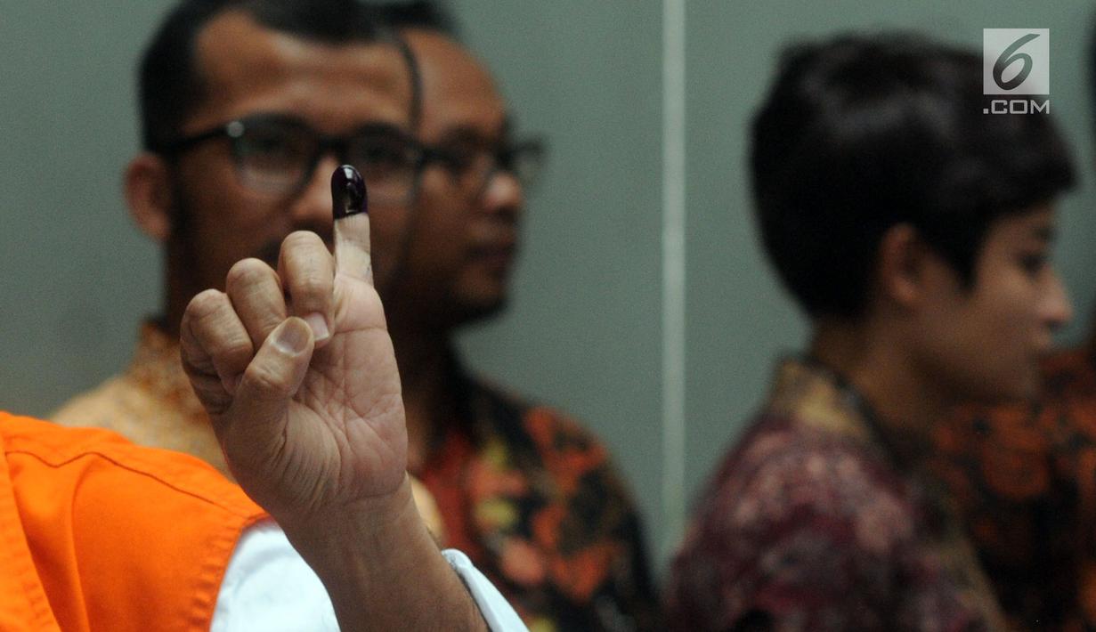 Salah satu tahanan KPK menunjukkan  jarinya yang sudah dicelup tinta usai melakukan pencoblosan di TPS 012 Guntur, Jakarta Selatan, Rabu (17/4). Sebanyak 63 tahanan KPK dengan memakai borgol tangan dan rompi oranye ikut menyalurkan hak pilihnya dalam Pemilu 2019. (merdeka.com/Dwi Narwoko)