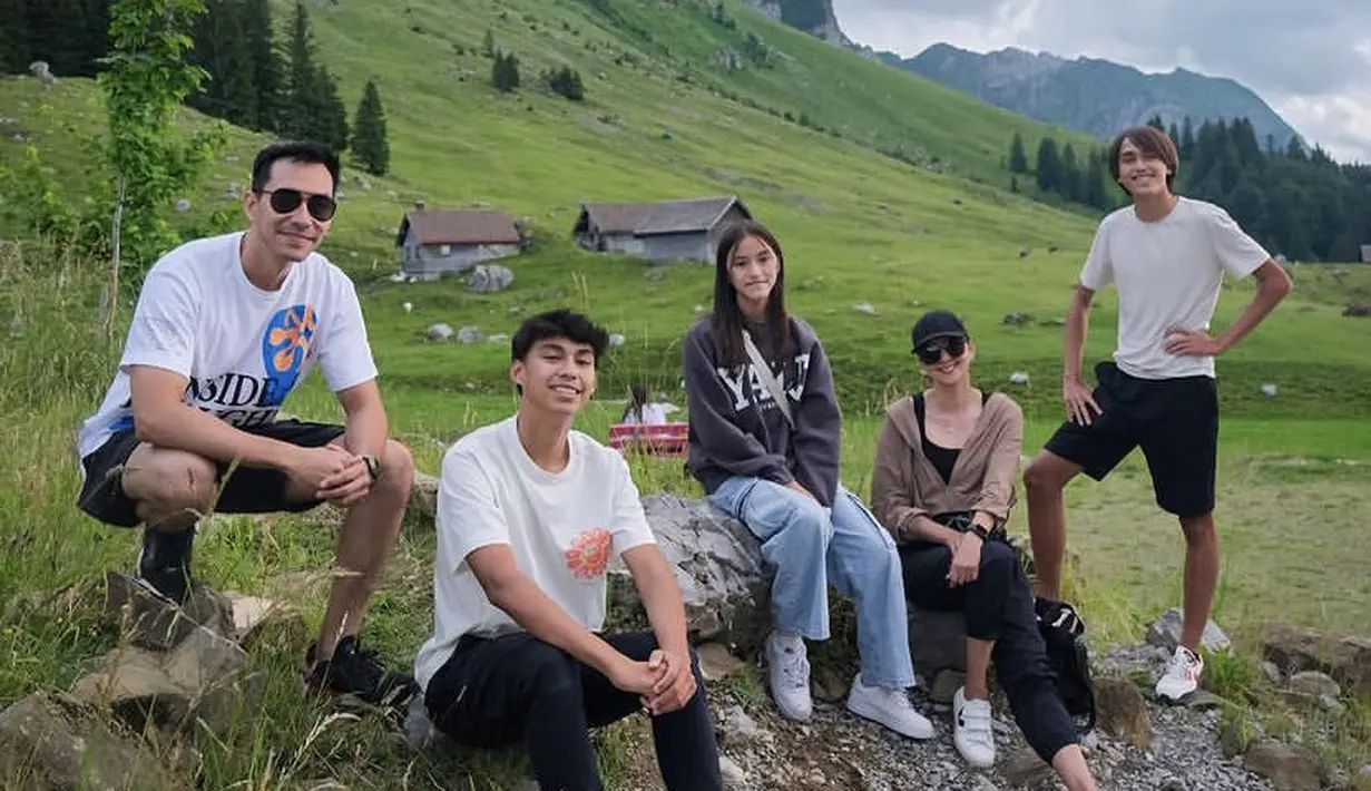 Keluarga Darius dan Donna Agnesia tampil dengan pakaian santai saat menikmati keindahan pemandangan hijau di Swiss. [Instagram/darius_sinathrya]