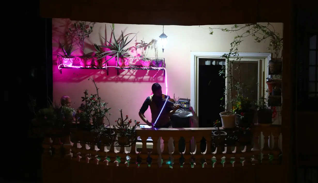 Pemain biola asal Mesir Mohammed Adel membawakan konser biola dari atas balkon di Kairo, pada 31 Maret 2020. Setiap malam, pemain biola itu menampilkan konser langsung dari balkonnya untuk menghibur para tetangganya selama jam malam nasional yang diberlakukan akibat COVID-19. (Xinhua/Ahmed Gomaa)