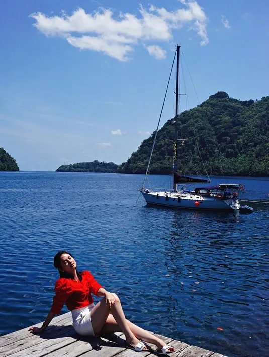 Dengan latar belakang sebuah kapal dan laut biru yang sangat indah, Clara berpose di sebuah dermaga. Menggunakan baju merah dan celana pendek putih membuat pemain film Sebelum Iblis Menjemput ini tampak semakin cantik diterangi sinar matahari. (Liputan6.com/IG/clarabernadeth)