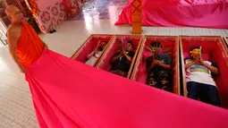 Seorang biksu menutup para pemuja dengan kain ketika berbaring dalam peti mati di kuil Takien, pinggiran Bangkok, Thailand, Senin (31/12). Upacara agama ini bagian dari ritual untuk menerima kematian yang tidak bisa dihindari manusia (AP/Sakchai lalit)