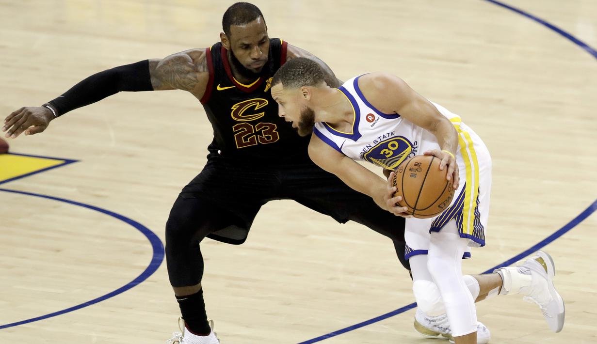 Pemain Cavaliers, LeBron James 9kiri) berusaha menutup pergerakan pemain Warriors, Stephen Curry pada gim pertama final NBA basketball di Oakland, California, (31/5/2018). Warriors menang 124-114. (AP/Marcio Jose Sanchez)