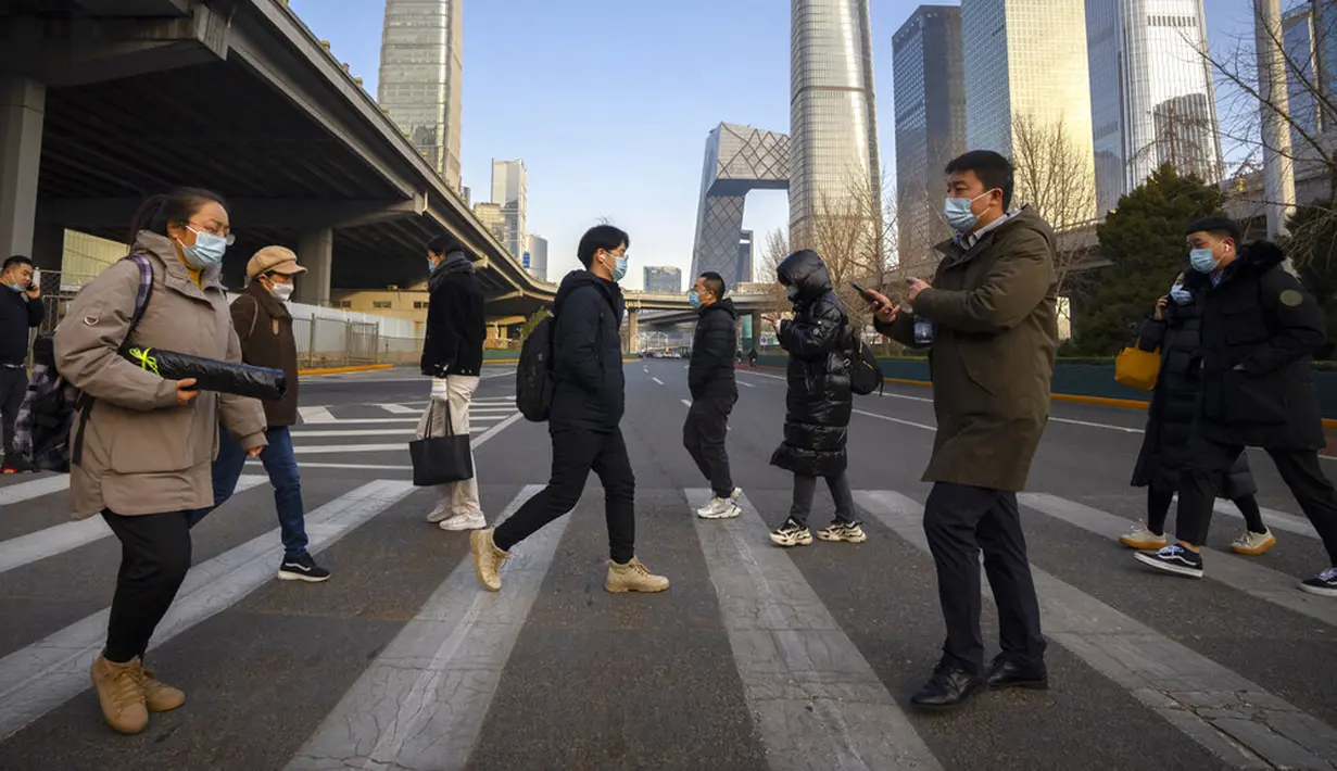 Para komuter yang mengenakan masker untuk melindungi diri dari COVID-19 menyeberang jalan di Beijing, China, Rabu (15/12/2021). China mendeteksi kasus kedua varian omicron pada seorang pria berusia 67 tahun yang dinyatakan positif setelah lebih dari dua minggu karantina. (AP Photo/Mark Schiefelbein)