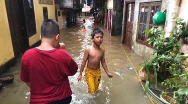 Anak-anak bermain di tengah banjir yang merendam kawasan Kebon Pala, Jakarta Timur, Selasa (25/2/2020). Akibat banjir yang tak kunjung surut, aktivitas warga di kawasan tersebut menjadi terganggu, terlebih dengan adanya pemadaman listrik. (Liputan6.com/Immanuel Antonius)