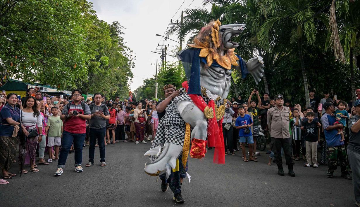 Sebagai informasi, ogoh-ogoh merupakan karya seni patung dalam kebudayaan Bali yang menggambarkan kepribadian Bhuta Kala. Tampak dalam foto, para penganut Hindu membawa Ogoh-ogoh, patung yang melambangkan roh jahat, selama pawai menjelang Nyepi di Surabaya pada Rabu 18 Maret 2026. (JUNI KRISWANTO/AFP)