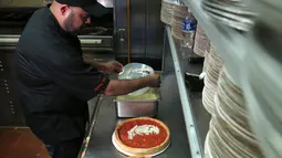 Chief Cook, Fabian Martinez menyelesaikan pembuatan pizza bergambar wajah calon presiden AS dari Partai Republik, Donald Trump dan rivalnya dari Partai Demokrat, Hillary Clinton di Giordano Pizzeria, Chicago, Selasa (27/9). (REUTERS / Jim Young)