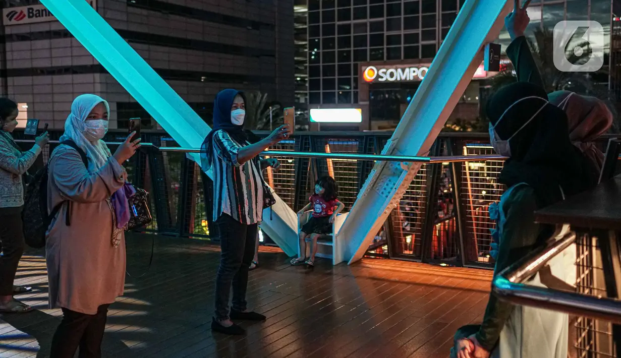 Warga berfoto di balkon Jembatan Penyeberangan Orang dan Sepeda (JPOS Phinisi) di kawasan Karet, Jakarta, Minggu (20/3/2022). JPOS Phinisi kini menjadi objek baru bagi warga Jakarta. (Liputan6.com/Faizal Fanani)
