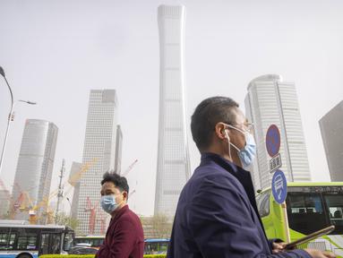Para komuter yang mengenakan masker berjalan saat badai debu dan pasir di kawasan pusat bisnis di Ibu Kota Beijing, China, Selasa (11/4/2023). Serangkaian badai debu dan pasir terbaru membuat indeks kualitas udara memburuk di Beijing pada Senin malam hingga Selasa. (AP Photo/Mark Schiefelbein)