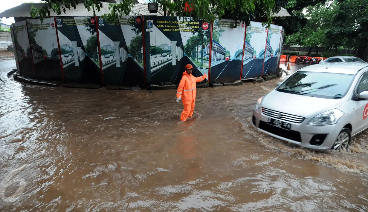 Petugas PPSU Kel Kuningan Barat mengatur lalu lintas di putaran kolong fly over Kapten Tendean, Jakarta, Selasa (9/2/2016). Hujan deras yang mengguyur Jakarta mengakibatkan putaran ini tergenang air. (Liputan6.com/Helmi Fithriansyah)
