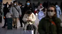 Seorang pemudik duduk di atas kopernya di luar pintu masuk Stasiun Kereta Api Beijing di Beijing, China, Sabtu (14/1/2023). Jutaan warga China diperkirakan akan melakukan perjalanan selama periode liburan Tahun Baru Imlek tahun ini. (AP Photo/Mark Schiefelbein)