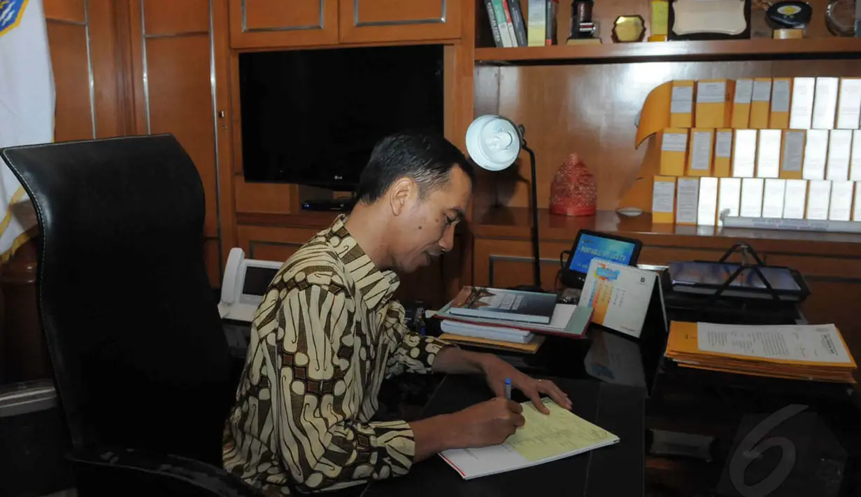 Jokowi tampak sibuk menyelesaikan tugasnya sebagai gubernur DKI dari balik meja, Jakarta, Rabu (17/9/14). (Liputan6.com/Herman Zakharia)
