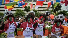 Para peserta yang mengenakan seragam tim sepak bola Portugal menyiapkan rujak uleg cingur, salad gurih tradisional khas Indonesia yang berisi moncong sapi dan sayuran, dalam Festival Rujak Uleg 2026 di Surabaya, Jawa Timur, Sabtu 9 Mei 2026. Pemerintah Kota Surabaya menggelar Festival Rujak Uleg 2026. (JUNI KRISWANTO/AFP)