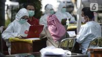 Petugas Puskesmas mendata warga yang mengikuti swab test di Balai RW 20, Villa Dago, Pamulang, Tangerang Selatan, Banten, Jumat (17/7/2020). Swab test gratis yang digelar seiring meningkatnya kasus COVID-19 tersebut diikuti 200 warga dari beberapa RW di Benda Baru. (merdeka.com/Dwi Narwoko)