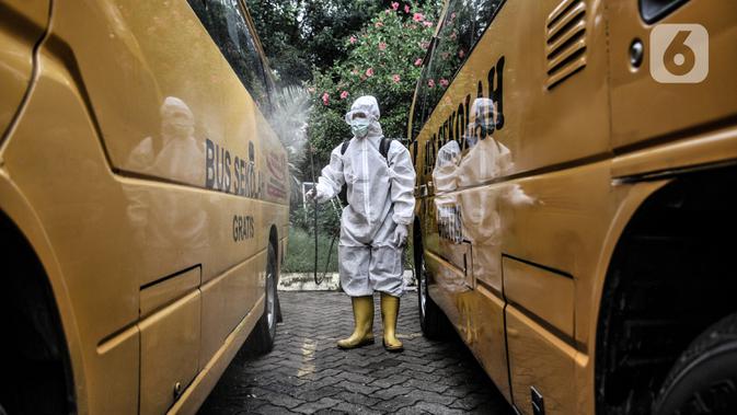 Petugas Kebersihan Bus (PKB) menyemprotkan disinfektan pada bus sekolah di Pool Unit Pelayanan Angkutan Sekolah (UPAS) DKI Jakarta, Kramat Jati, Selasa (5/1/2021). Sterilisasi bus sekolah rutin dilakukan usai digunakan mengangkut pasien terpapar Covid-19 ke RS rujukan. (merdeka.com/Iqbal Nugroho)