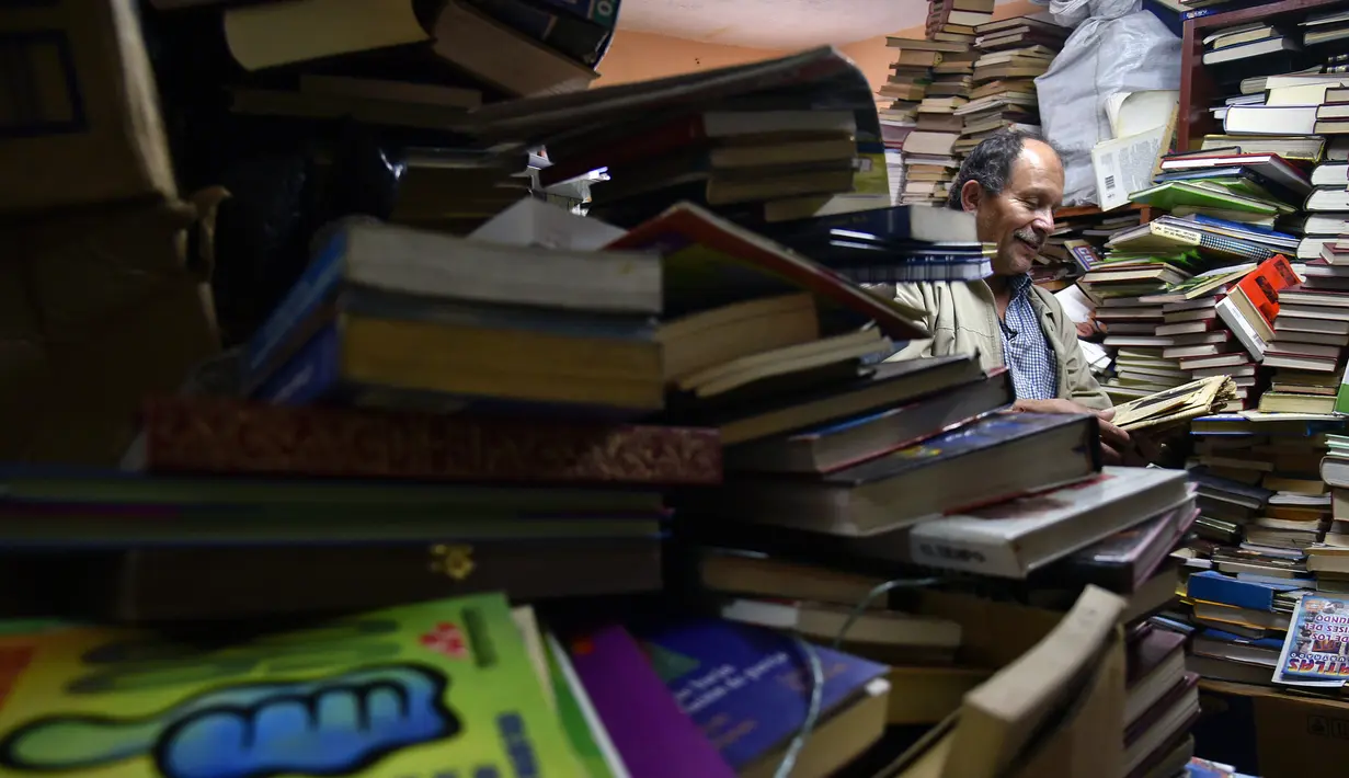 Jose Alberto Gutierrez memeriksa buku koleksinya yang ada di perpustakaan rumahnya di Bogota, 18 Mei 2017. Sekarang, Gutierrez akan kembali belajar untuk ujian sarjana di sekolahnya, yang pernah ditinggalkan karena kemiskinan. (GUILLERMO LEGARIA/AFP)