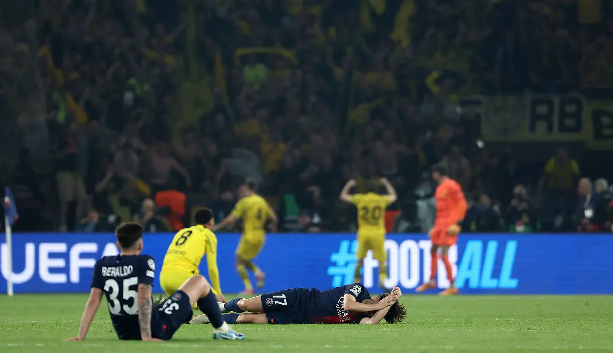 Pemain PSG, Vittinha (kanan) dan Lucas Beraldo terduduk lesu setelah timnya kalah dari Borussia Dortmund pada laga leg kedua semifinal Liga Champions 2023/2024 di Parc des Princes, Paris, Prancis, Rabu (08/05/2024) dini hari WIB. (AFP/Franck Fife)