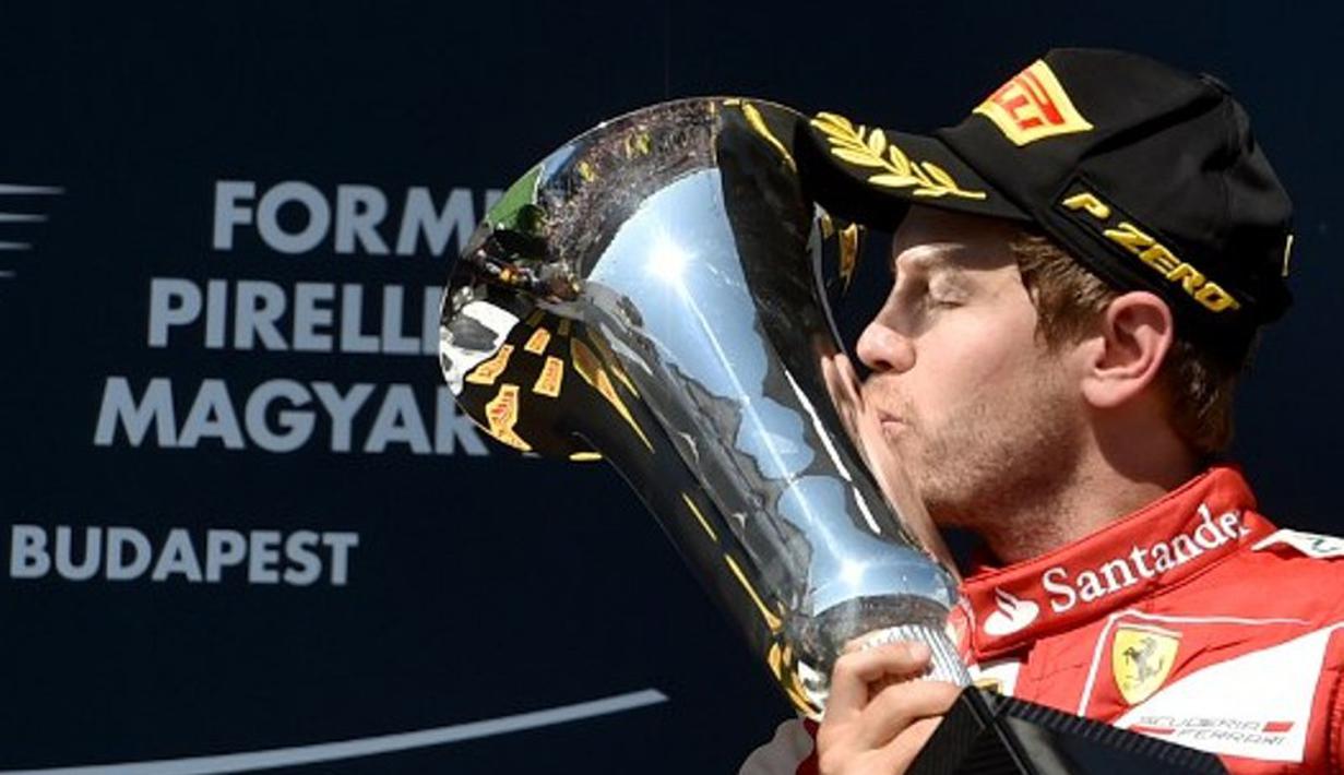 Pebalap Ferrari, Sebastian Vettel, mencium trofi juara F1 GP Seri Hungaria di Sirkuit Hungaroring, Budapest, Hungaria. (26/7/2015). (AFP PHOTO/Andrej Isakovic)