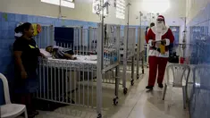Seorang pria berpakaian seperti Sinterklas berjalan menyusuri lorong untuk mengantarkan hadiah kepada anak-anak yang dirawat di ruang gawat darurat sebuah rumah sakit di lingkungan El Cementerio di Caracas, Venezuela pada 25 Desember 2023. (Pedro Rances Mattey / AFP)