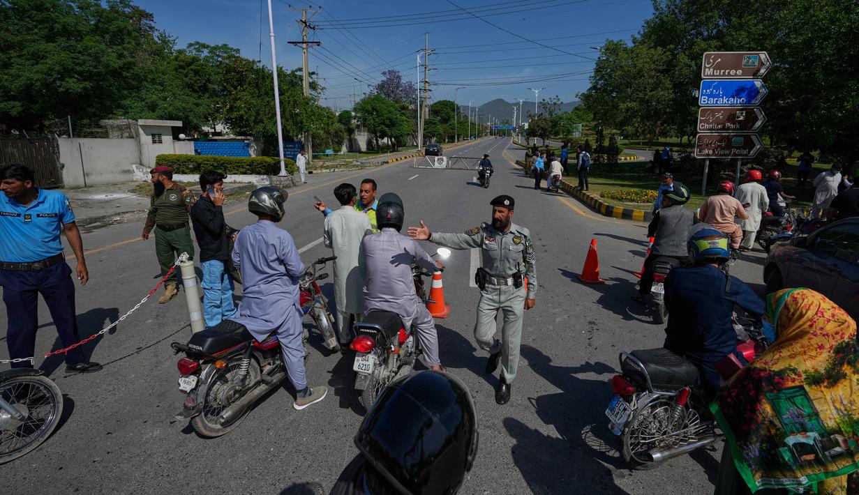 Akibat serangan tersebut, pemimpin tertinggi Iran, Ayatollah Ali Khamenei gugur. Tampak dalam foto, petugas polisi mengalihkan pengendara sepeda motor di jalan yang dibarikade menjelang putaran kedua negosiasi antara Amerika Serikat dan Iran, di Islamabad, Pakistan, Senin 20 April 2026. (AP Photo/Anjum Naveed)