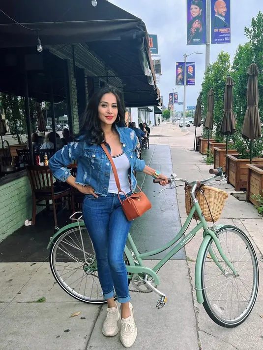 Berpose dengan sepeda, Diah Permatasari menghadirkan nuansa kasual melalui pilihan outfitnya kali ini. Atasan putih, dipadu dengan jaket dan celana jeans, serta sling bagi cokelat dan sneakers bernuansa broken white yang menjadikan Diah Permatasari di foto ini tak terlihat berusia 52 tahun sama sekali. Foto: Instagram.