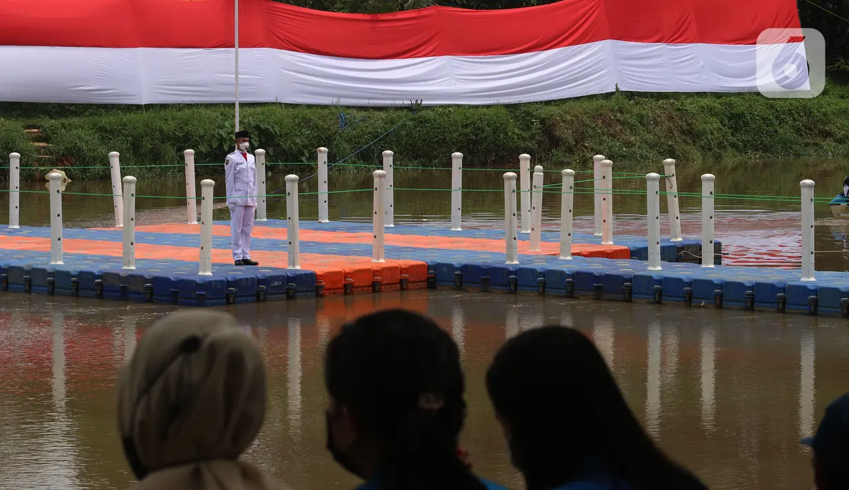 Warga saat menyaksikan pengibaran bendera merah putih di Sungai Cisadane, Kota Tangerang, Banten, Kamis (28/10/2021). Pengibaran bendera merah putih yang di ikuti puluhan pemuda tersebut di lakukan untuk memperingati hari sumpah pemuda. (Liputan6.com/Angga Yuniar)