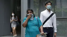 Pekerja memakai masker saat berjalan di pusat bisnis, Singapura (25/9/2015). Menurut Badan Lingkungan Nasional Singapura kabut Polutan Standar Indeks (PSI) mencapai tinggi 341 pada hari Jumat. (REUTERS/Edgar Su)