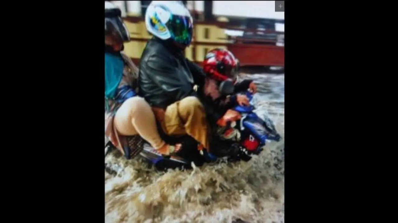 Pengendara sepeda motor saat melewati hujan