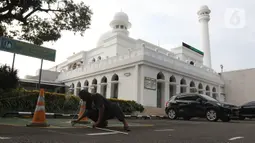 Pekerja membuat garis saf sholat Idul Fitri di Masjid Al Azhar, Jakarta, Rabu (11/5/2021). Masjid Al Azhar akan menggelar sholat idul Fitri secara berjamaah di lapangan masjid tersebut dengan protokol pencegahan COVID-19 yang ketat. (Liputan6.com/Herman Zakharia)