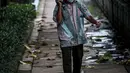 Seorang pedagang berjalan di Kawasan Sudirman, Jakarta, Kamis, (17/2/2022). Kepala BPBD DKI Jakarta Isnawa Adji mengatakan, Menteri Kesehatan (Menkes) Budi Gunadi Sadikin sudah memberikan sinyal bahwa DKI telah melewati pandemi gelombang ketiga. (Liputan6.com/Faizal Fanani)