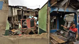 Seorang laki-laki menunjukan rumah yang rubuh dikawasan muara baru, Jakarta, Jumat (13/2/2015).  Sebanyak 33 rumah di muara baru Jakarta Utara mengalami kemiringan parah dan 2 buah rumah ambruk akibat banjir. (Liputan6.com/Faizal Fanani)