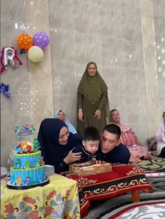 Athar pun meniup lilin yang tertancap di kue ulang tahunnya dibantu sang ayah, Rezky Aditya. Sementara, Citra Kirana menahan tubuh sang anak agar tidak tersenggol kue. (Foto: Instagram/@thereal_rezkyadhitya)