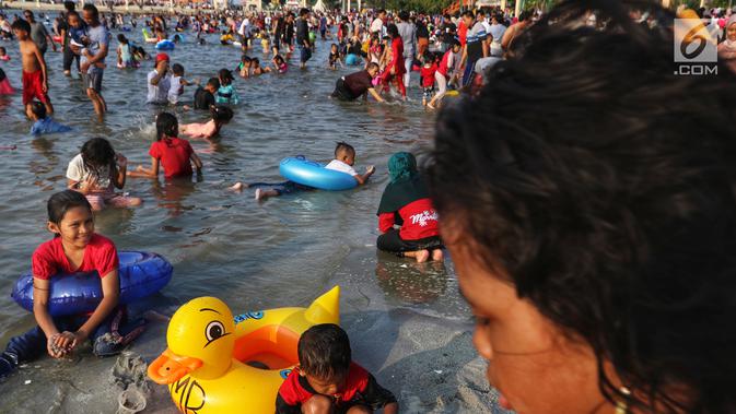 Pengunjung bermain dan berenang di kawasan Beach Pool, Taman Impian Jaya Ancol, Jakarta, Kamis (6/6/2019). Hari kedua Lebaran banyak dimanfaatkan warga untuk berlibur dan berekreasi bersama keluarga atau kerabat dengan mengunjungi pantai Ancol. (Liputan6.com/Johan Tallo)