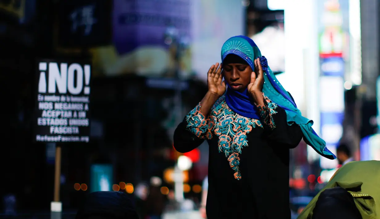 Seorang wanita menunaikan salat saat unjuk rasa bertajuk 'I Am A Muslim Too' di Times Square pada 19 Februari 2017 di New York City, AS, Minggu (19/2). (AFP Photo/ Eduardo Munoz Alvarez) 