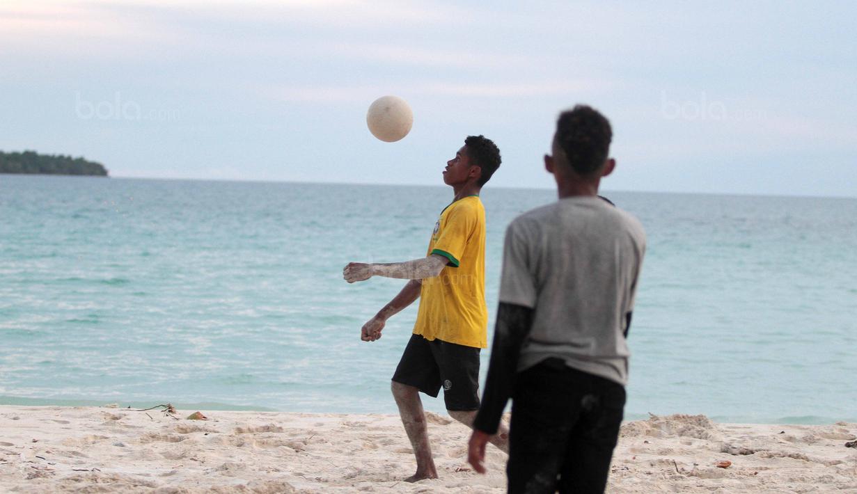 Seorang pemuda melakukan kontrol bola saat bermain bola dekat pantai di Desa Matwaer, Kei Kecil, Maluku (25/12/2017). Bermain bola di pasir menjadi daya tarik tersendiri bagi anak-anak dan pemuda desa. (Bola.com/Nick Hanoatubun)