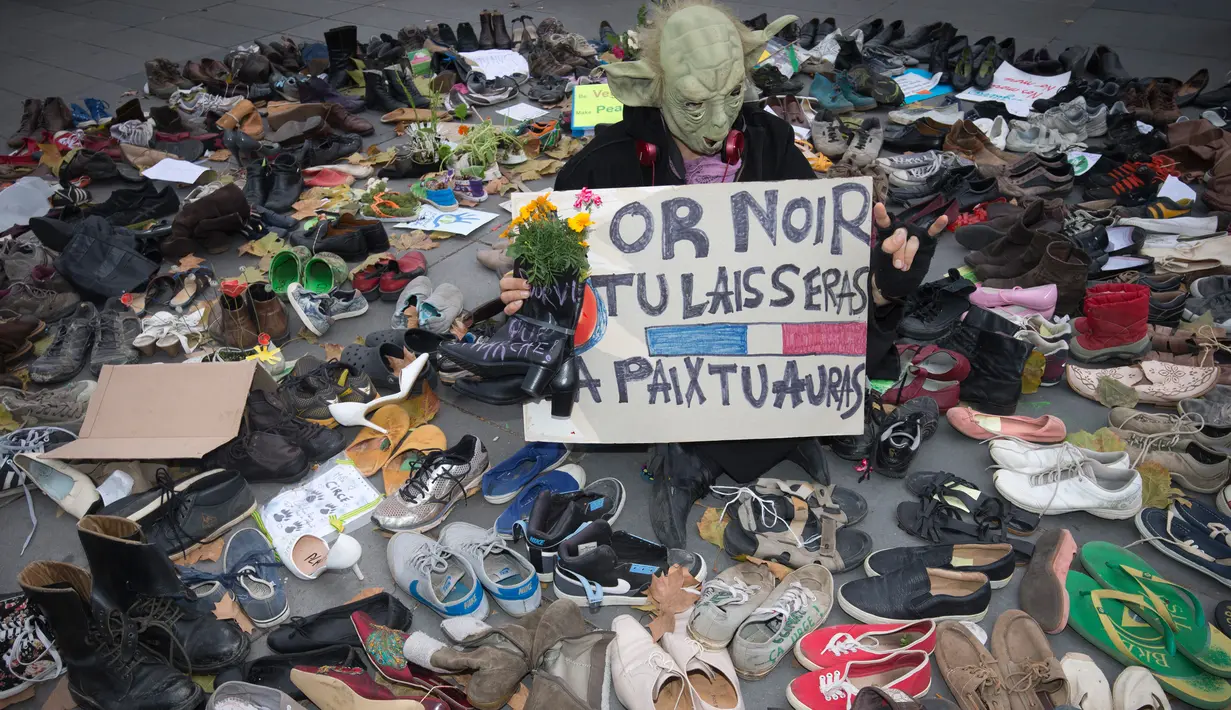 Seorang pria berpakaian seperti Yoda berdiri diantara sepatu yang dipajang di place de la Republique, Prancis, sebagai tanda solidaritas karena pawai lingkungan di Paris dibatalkan jelang KTT Perubahan Iklim, Minggu (29/11).(AFP PHOTO/Joel SAGET)