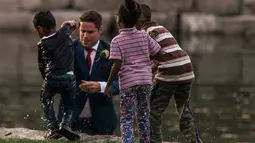 Calon pengantin pria, Clayton Cook tanpa mempedulikan setelan jasnya langsung terjun ke sungai dan menarik seorang bocah yang nyaris tenggelam ke tepian sungai. (HATT PHOTOGRAPHY / Facebook)