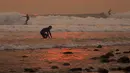 Sejumlah orang berselancar di pantai Carpinteria, California (12/12). Warnya oranye keemasan tersebut karena cahaya matahari yang terhalang oleh asap kebakaran dari Api Thomas. (David McNew / Getty Images / AFP)