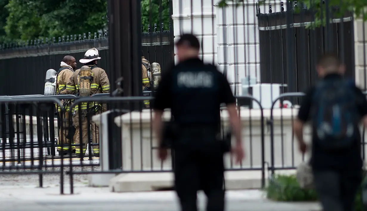 Petugas pemadam kebakaran berdiri di depan gerbang bagian utara Gedung Putih, Washington, DC, Senin (30/5). Gedung Putih ditutup sebagian untuk menyelidiki sebuah benda mencurigakan yang dilemparkan melalui pagar. (Brendan Smialowski/AFP)