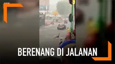 Sebelum membantu pengguna jalan yang mengalami kesulitan saat banjir, pria ini malah berenang terlebih dahulu. Aksinya pun mengundang tawa warga.